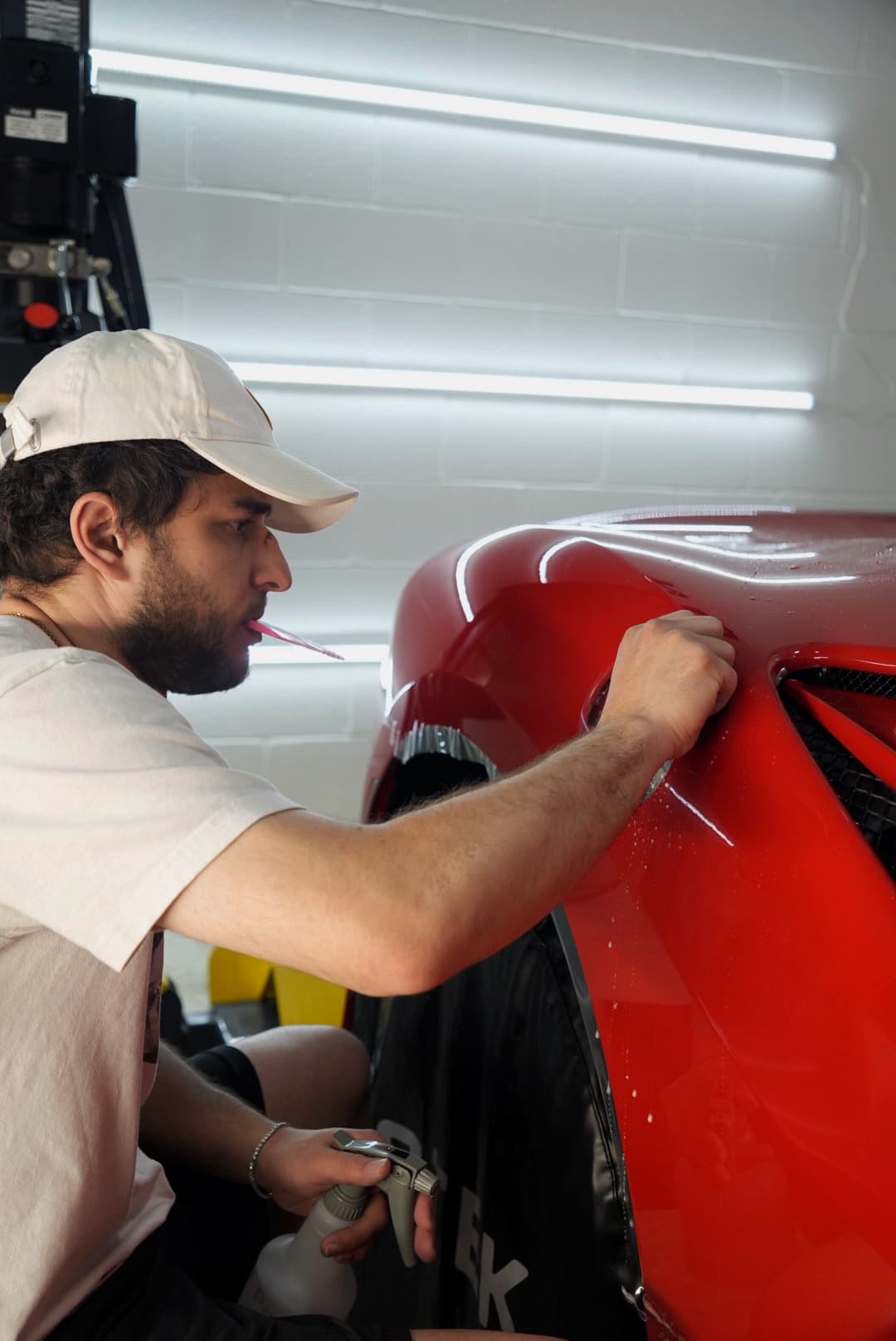 Diamond Detailz installer applying STEK PPF to the rear quarter panel of a red Ferrari
