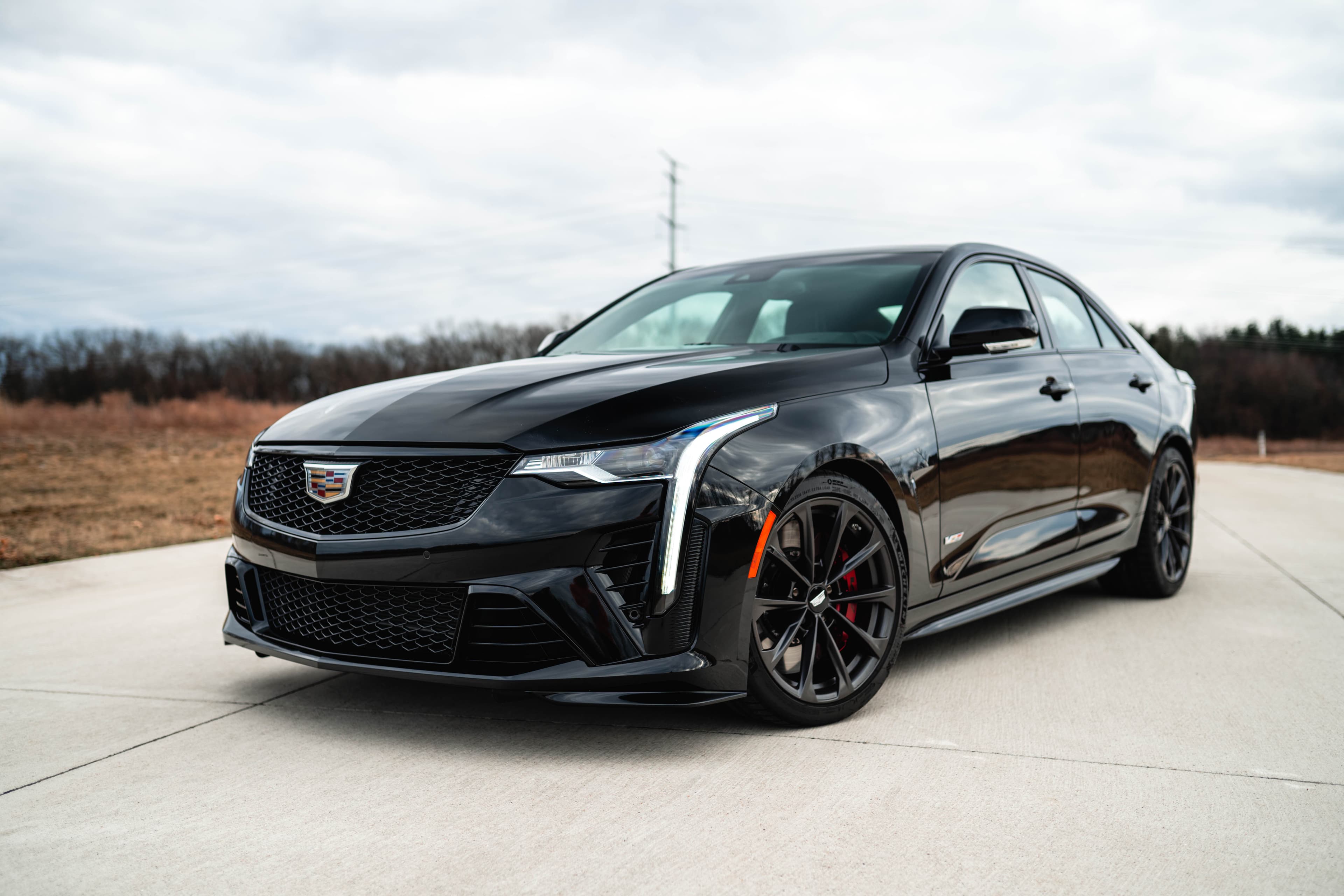 Black Cadillac CT4-V, front three-quarter, on a concrete lot