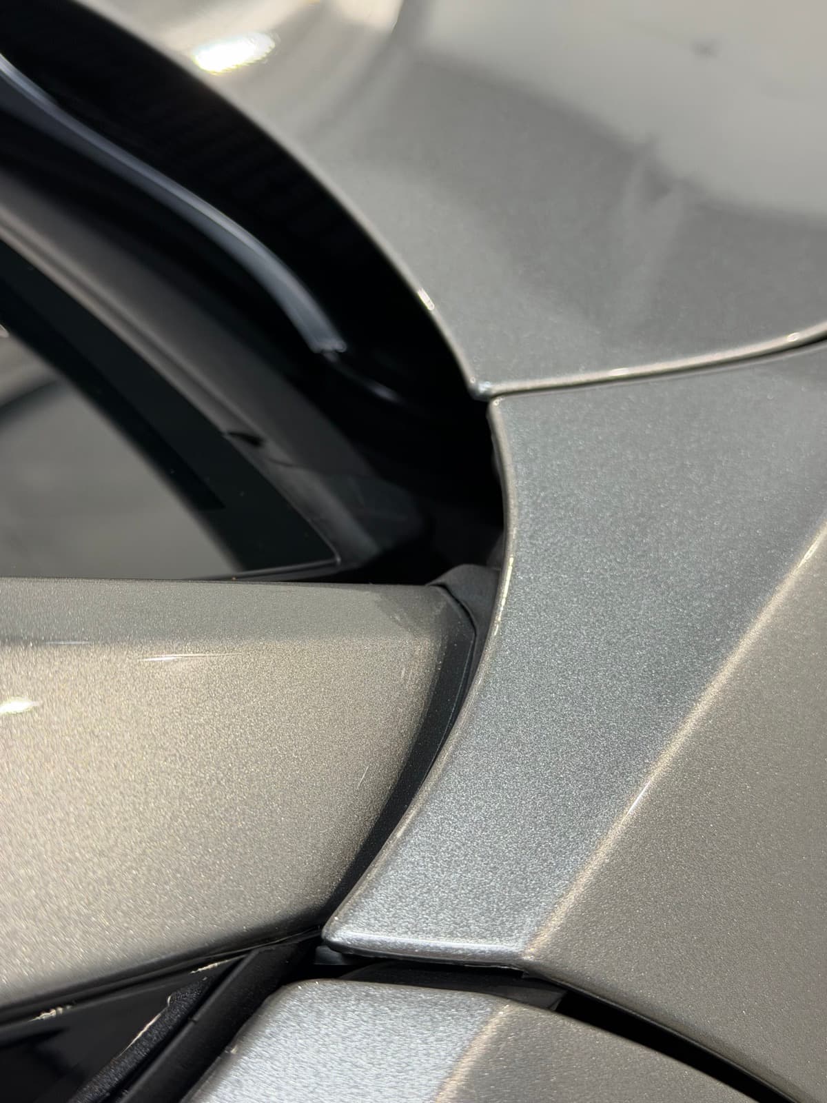 Aston Martin silver panel meeting black gloss trim with crisp shop-light reflections — proves the PPF top coat stays optically clear over metallic paint